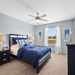 Large bedroom with dresser and queen bed in model at Pines