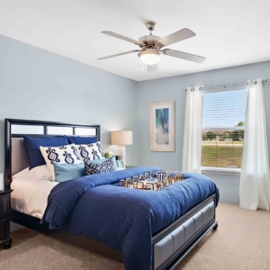 Large bedroom in model home at Pines with ceiling fan and good natural light